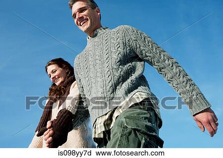 Stock Image - Mid adult couple holding hands. Fotosearch