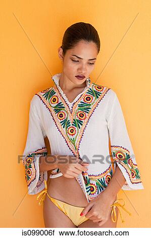 Stock Image - Woman against yellow wall. Fotosearch
