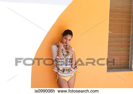 Stock Image - Woman against yellow wall. Fotosearch