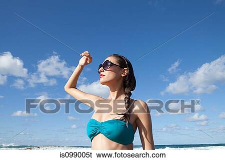 Stock Photograph - Woman on beach wearing sunglasses. Fotosearch