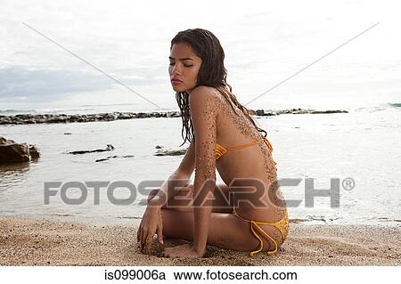Stock Image - Woman sitting on beach. Fotosearch