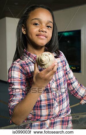 Stock Image - Girl holding sea shell in aquarium. Fotosearch
