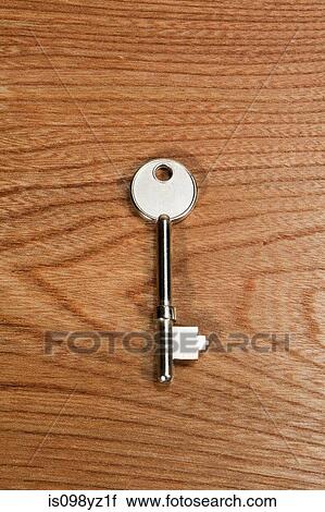 Stock Image - Key against wooden background. Fotosearch