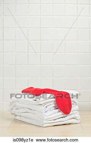 Stock Image - Piles of clean white laundry and red sock. Fotosearch