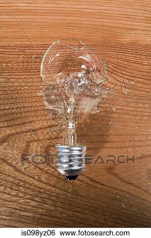 Stock Photograph - Smashed lightbulb against wooden background. Fotosearch