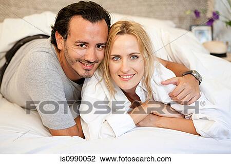 Couple lying on bed and looking at camera View Large Photo Image Stock Image - Couple lying on bed and looking at camera. Fotosearch