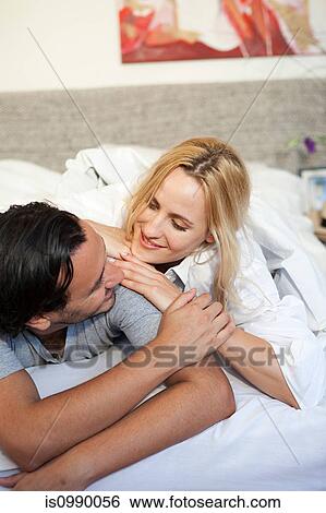 Couple relaxing on bed View Large Photo Image Stock Photograph - Couple relaxing on bed. Fotosearch