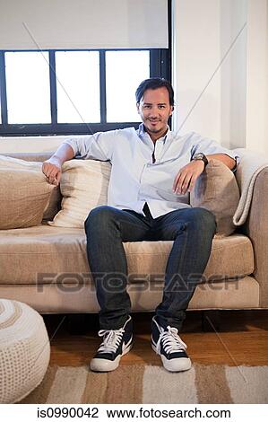 Stock Image - Man sitting on sofa. Fotosearch