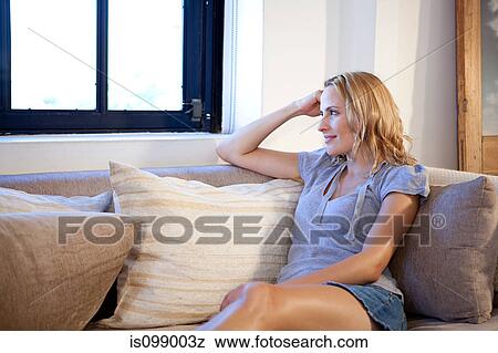 Woman sitting on sofa and looking away View Large Photo Image Stock Photo - Woman sitting on sofa and looking away. Fotosearch