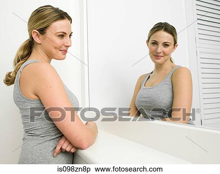 Stock Photography - Reflection of young woman in bathroom mirror. Fotosearch