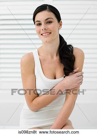 Stock Photograph - Young woman in bathroom touching arm. Fotosearch