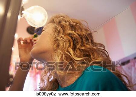 Stock Photo - Teenage girl applying mascara in mirror. Fotosearch