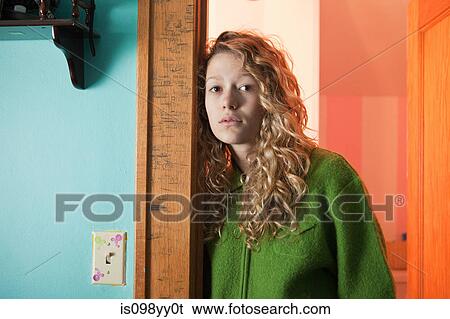 Stock Photograph - Teenage girl leaning in doorway, portrait. Fotosearch
