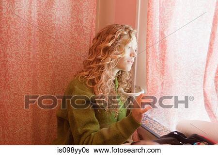 Stock Photograph - Teenage girl looking out of bathroom window. Fotosearch