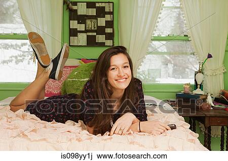 Stock Image - Teenage girl lying on bed, portrait. Fotosearch