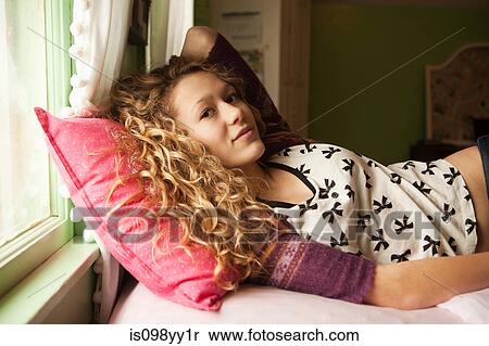 Stock Photography - Teenage girl lying on bed, portrait. Fotosearch