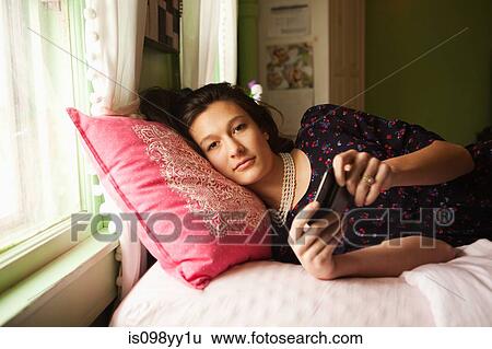 Teenage girl lying on bed with smartphone View Large Photo Image Stock Photograph - Teenage girl lying on bed with smartphone. Fotosearch