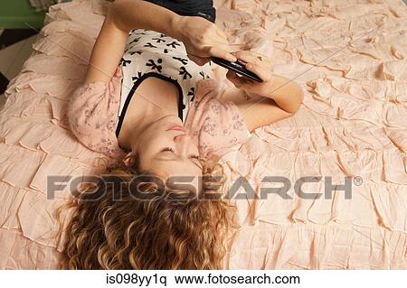 Stock Photography - Teenage girl lying on bed with smartphone. Fotosearch