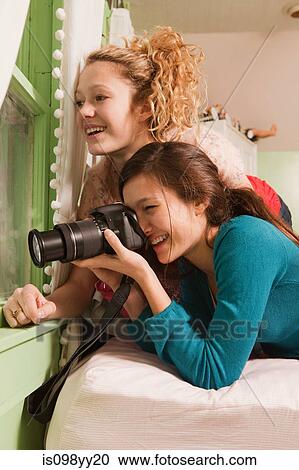Teenage girls looking through window taking photograph View Large Photo Image Stock Image - Teenage girls looking through window taking photograph. Fotosearch