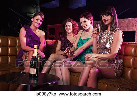 Stock Photography - Four young women enjoying champagne in nightclub. Fotosearch