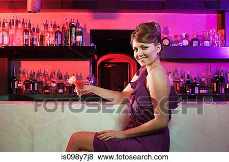 Happy young woman sitting at cocktail bar View Large Photo Image Stock Photo - Happy young woman sitting at cocktail bar. Fotosearch