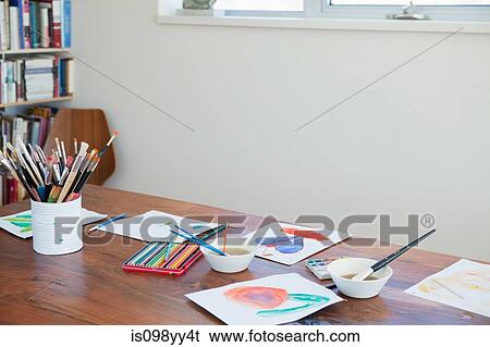 Stock Photograph - Children's paintbrushes and paintings on table. Fotosearch