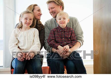 Stock Image - Family sitting on windowsill, portrait. Fotosearch