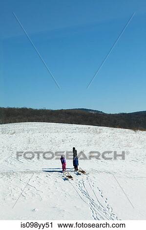 Stock Image - Mother and two children with toboggan. Fotosearch