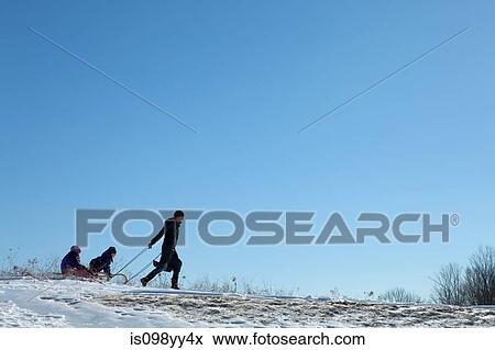 Stock Photo - Mother and two children with toboggan. Fotosearch