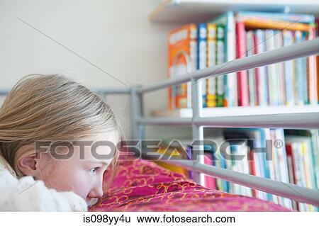 Stock Photograph - Young wistful girl lying on bed. Fotosearch