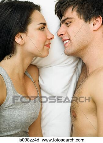 Young couple lying in bed face to face View Large Photo Image Stock Image - Young couple lying in bed face to face. Fotosearch