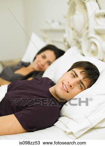 Young couple lying in bed View Large Photo Image Stock Image - Young couple lying in bed. Fotosearch