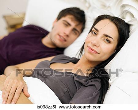 Young couple lying in bed View Large Photo Image Stock Image - Young couple lying in bed. Fotosearch