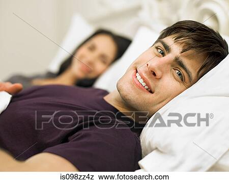Young couple lying in bed View Large Photo Image Stock Photo - Young couple lying in bed. Fotosearch