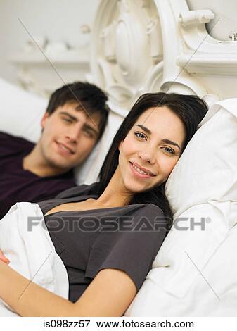 Young couple lying in bed View Large Photo Image Stock Photo - Young couple lying in bed. Fotosearch