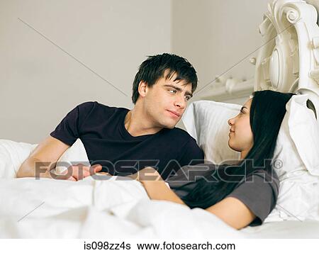 Young couple lying in bed View Large Photo Image Stock Photograph - Young couple lying in bed. Fotosearch