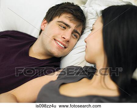 Stock Photograph - Young couple lying in bed. Fotosearch