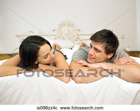 Young couple lying on bed face to face View Large Photo Image Stock Image - Young couple lying on bed face to face. Fotosearch