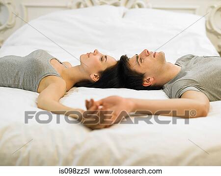 Young couple lying on bed holding hands View Large Photo Image Stock Image - Young couple lying on bed holding hands. Fotosearch