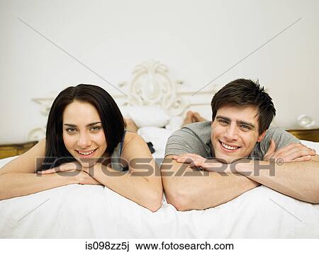 Young couple lying on bed, portrait View Large Photo Image Stock Image - Young couple lying on bed, portrait. Fotosearch