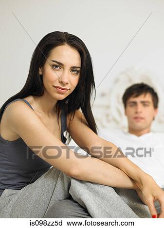 Young couple sitting on bed, focus on foreground View Large Photo Image Stock Image - Young couple sitting on bed, focus on foreground. Fotosearch