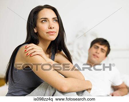 Young couple sitting on bed, focus on foreground View Large Photo Image Stock Photography - Young couple sitting on bed, focus on foreground. Fotosearch