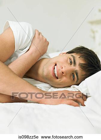 Stock Image - Young man lying on bed. Fotosearch