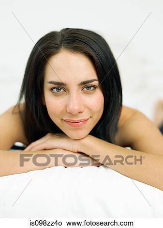 Picture - Young woman lying on bed, portrait. Fotosearch