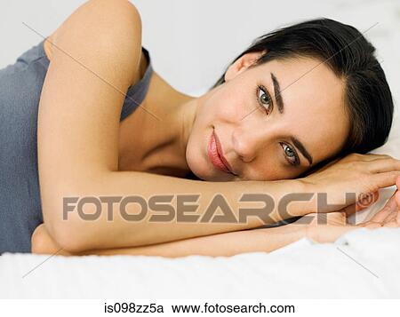 Young woman lying on bed, portrait View Large Photo Image Stock Image - Young woman lying on bed, portrait. Fotosearch
