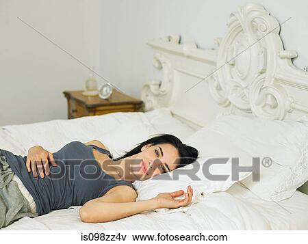 Young woman lying on bed View Large Photo Image Stock Photo - Young woman lying on bed. Fotosearch