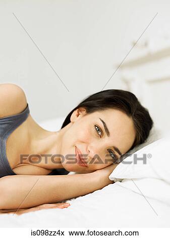 Stock Photo - Young woman lying on bed. Fotosearch
