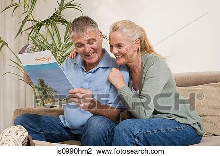Stock Image - Mature couple with holiday brochure. Fotosearch