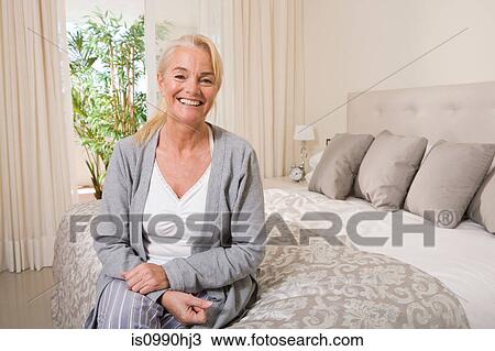 Mature woman sitting on bed View Large Photo Image Stock Image - Mature woman sitting on bed. Fotosearch