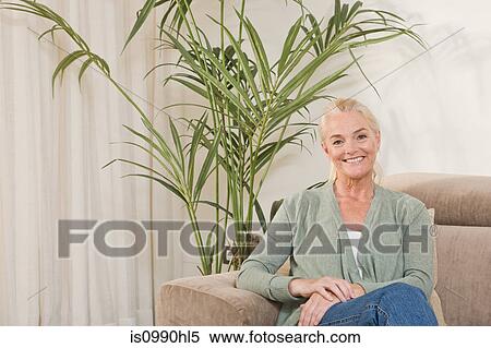 Mature woman sitting on sofa View Large Photo Image Stock Photography - Mature woman sitting on sofa. Fotosearch
